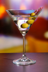Martini with green olives on table in bar