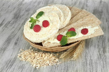 Tasty crispbread with berries in wicker basket, on wooden table