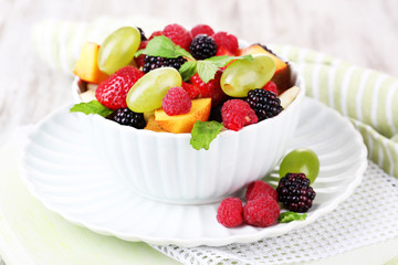 Fruit salad in bowl, on wooden background