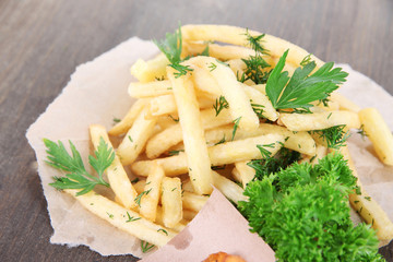 French fries on tracing paper on wooden table