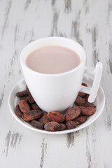 Cocoa drink and cocoa beans on wooden background