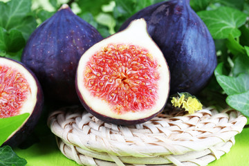 Ripe figs in leaves on wooden table close-up