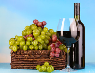 Ripe green and purple grapes in basket with wine