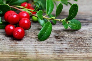 Fresh Cowberries with some leaves on wooden background