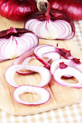 Fresh red onions on cutting board close up