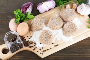 Meat patties on board on wooden table