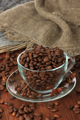 Coffee beans in cup on wooden background