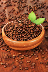 Coffee beans in bowl on wooden background