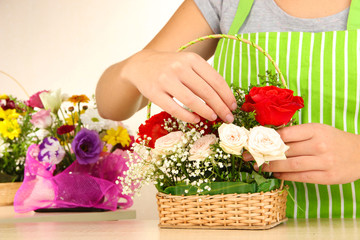 Florist makes flowers bouquet in wicker basket