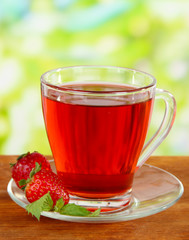 Delicious strawberry tea on table on bright background