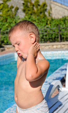 Young boy applying suntan lotion