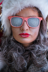 Woman wearing Santa Claus hat and sunglasses listening to music