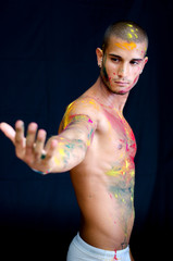 Attractive young man shirtless, skin painted with bright colors