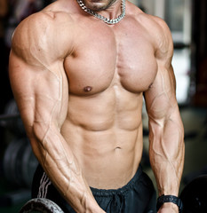 Fototapeta na wymiar View of muscular torso of male bodybuilder in gym