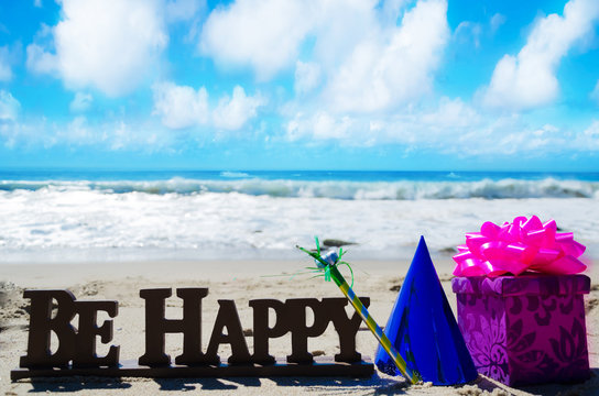Sign "Be Happy" with Birthday decorations on the beach