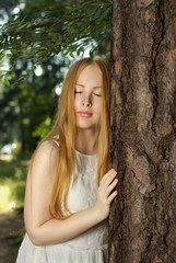 A young girl with long blond hair, standing in the forest