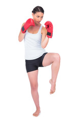 Healthy model with boxing gloves kicking