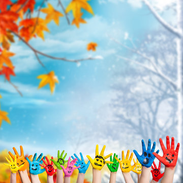 angemalte Kinderhände vor Herbst- und Winterhintergrund