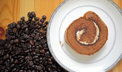 Jam roll and coffee beans on wooden