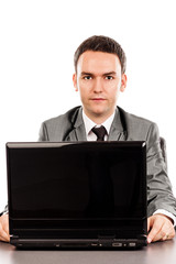 Young businessman sitting at office desk and looking at camera