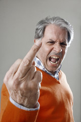 Älterer Mann zeigt den Stinkefinger. Schreit wütend.