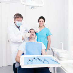 Dental surgery. There is a dentist, his assistant and the patien