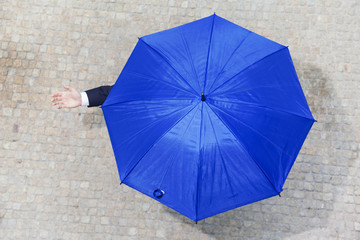 Confident businessman hidden under umbrella and checking if it's