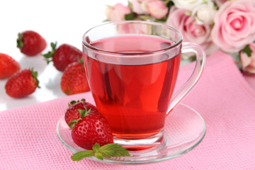 Delicious strawberry tea on table on white background