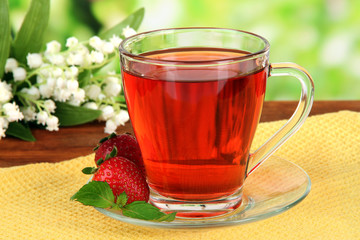 Delicious strawberry tea on table on bright background