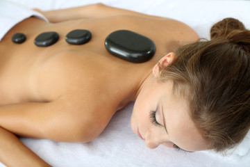 Obraz na płótnie Canvas Beautiful young woman having stone massage in spa salon
