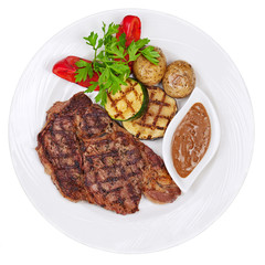 Grilled steaks, baked potatoes and vegetables on white plate on