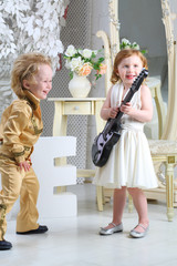 Little children in pop retro suit laugh and playing the guitar