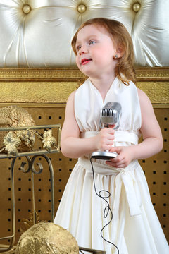 A little girl in white dress with microphone, retro style