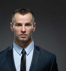 Front view of self-confident manager in dark suit with black tie