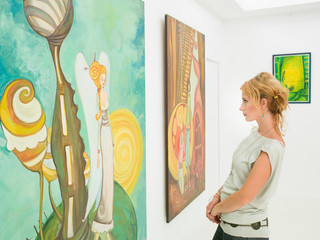 woman contemplating paintings in art gallery