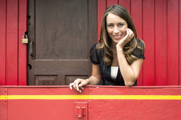 Woman Leaning On Railing In Red Caboose Car