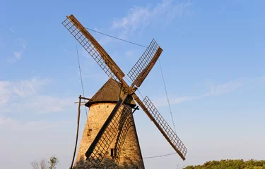 Foto op Plexiglas Molens Oude houten molen tegen de blauwe lucht