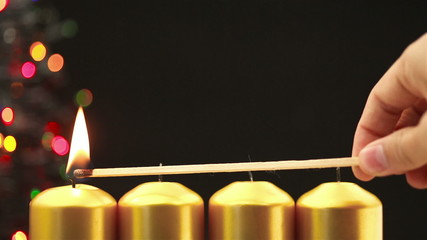 Hand lighting four christmas candles for advent