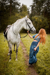 Obraz na płótnie Canvas The girl with red hair and a white horse