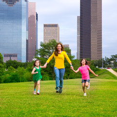 Mother and daughters walking holding hands on city skyline