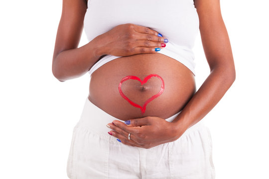 Young pregnant black woman touching her painted belly - African