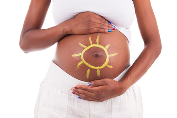 Young pregnant black woman touching her painted belly - African