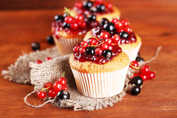 Tasty muffins with berries on wooden table