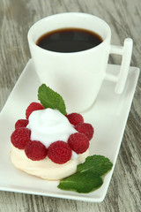 Tasty meringue cake with berries and cup of coffee,