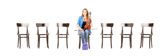 Casual woman seated on a chair holding a violin and waiting