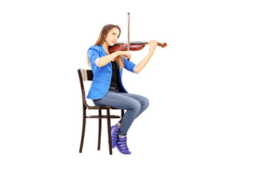 Casual young woman seated on a wooden chair playing the violin © Ljupco Smokovski