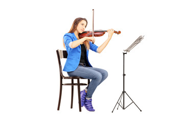 Young woman on a wooden chair playing the violin