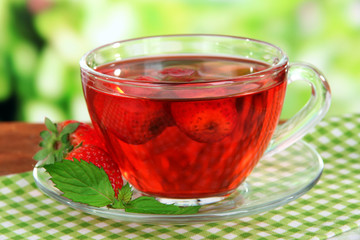 Delicious strawberry tea on table on bright background