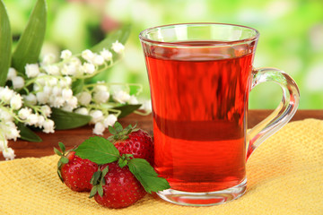 Delicious strawberry tea on table on bright background