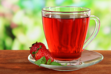 Delicious strawberry tea on table on bright background